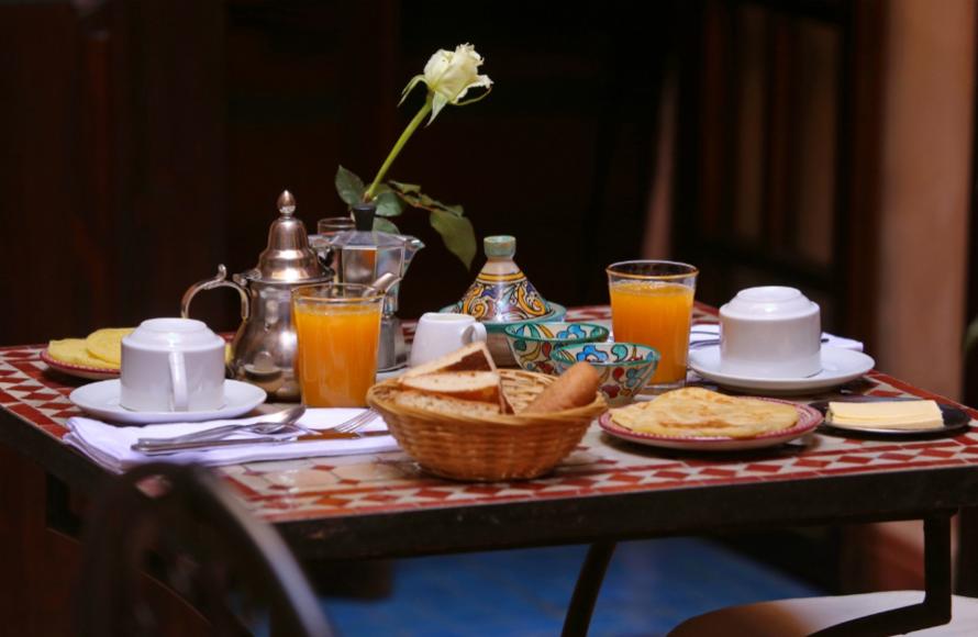 Colazione con tè, succo d'arancia, pane e dolci su tavolo decorato.